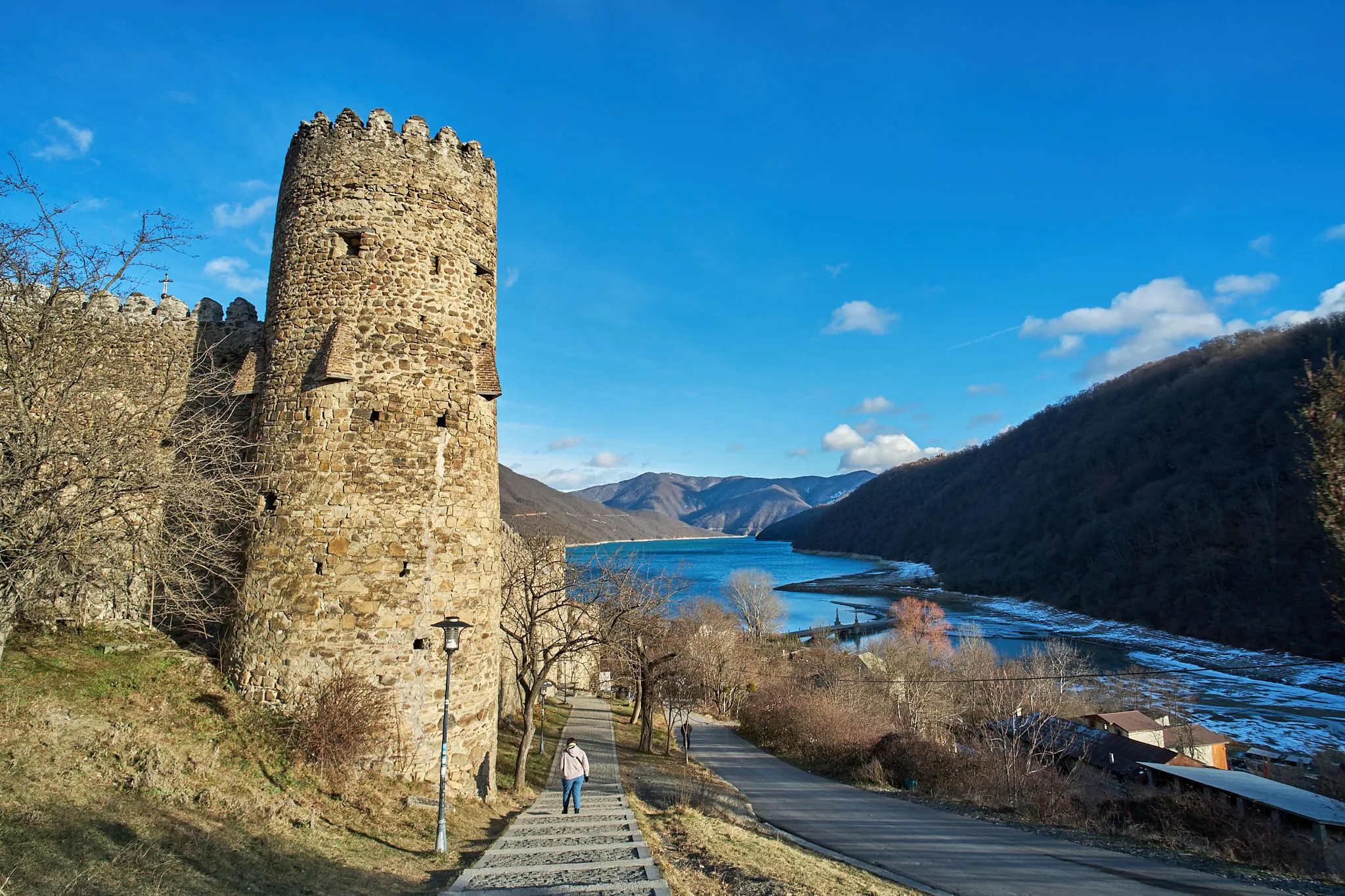 A round stone fortress tower above a path leading down to the water