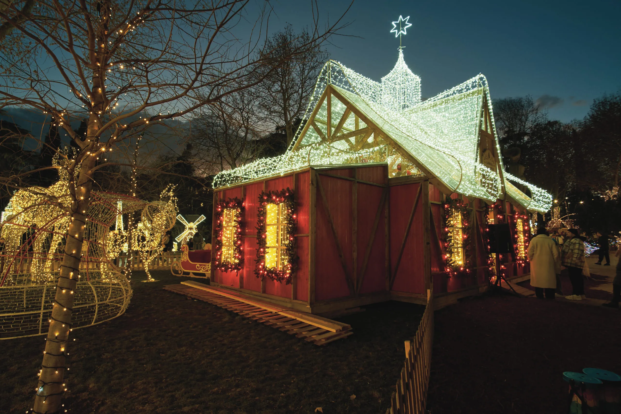 A Christmas market pavilion lit up at night among decorated trees