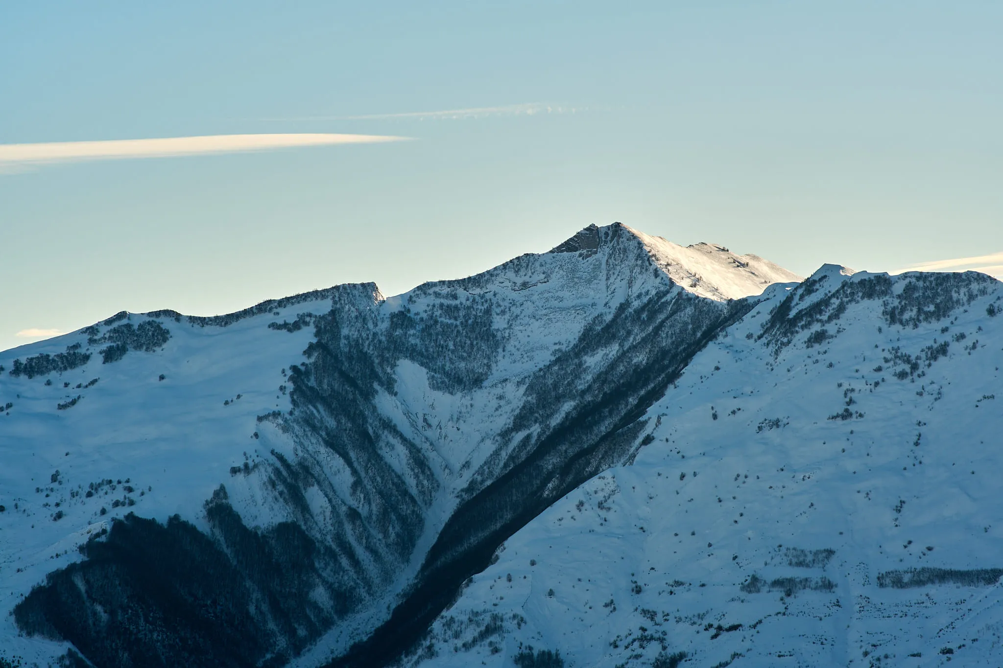 A snow-covered ridge seen at long range in cold blue light