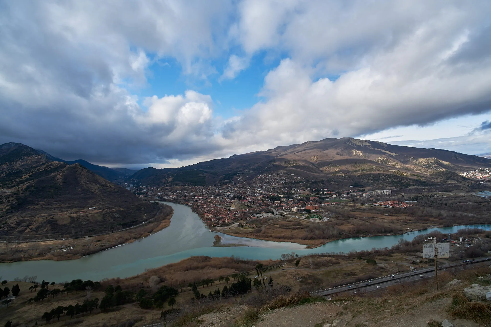 Two rivers meeting below a town, seen from a hillside under heavy cloud